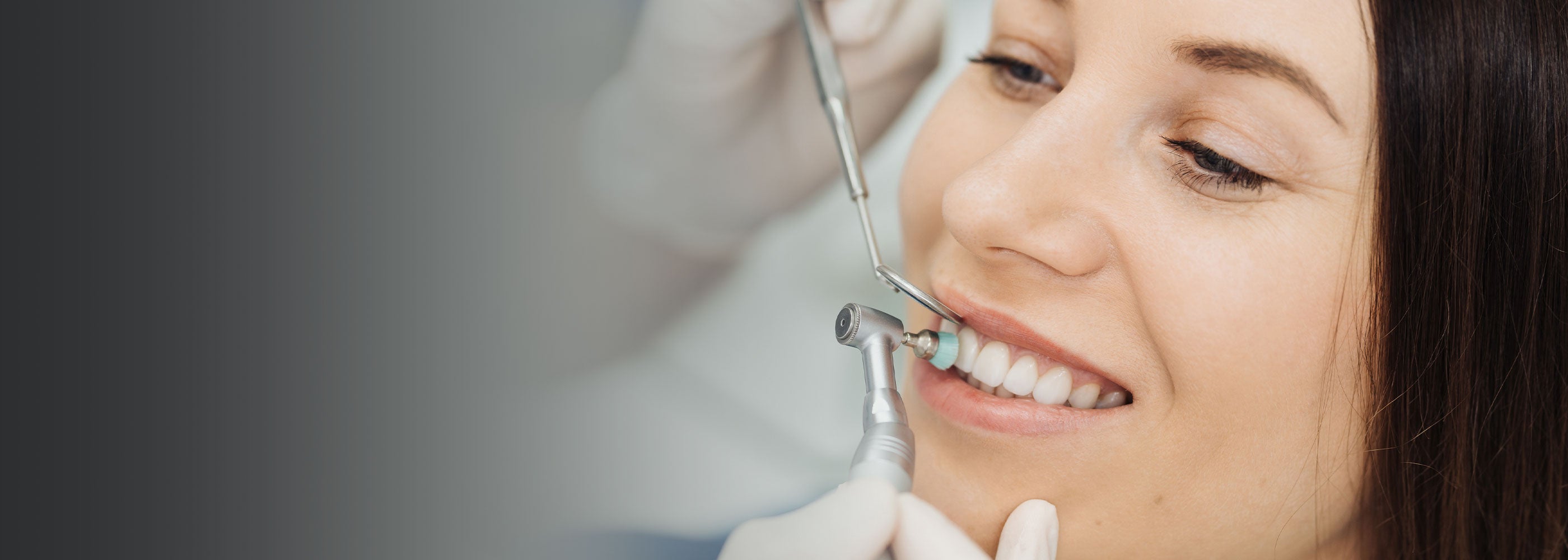 Patient having dental hygiene treatment, having her teeth cleaned and polished